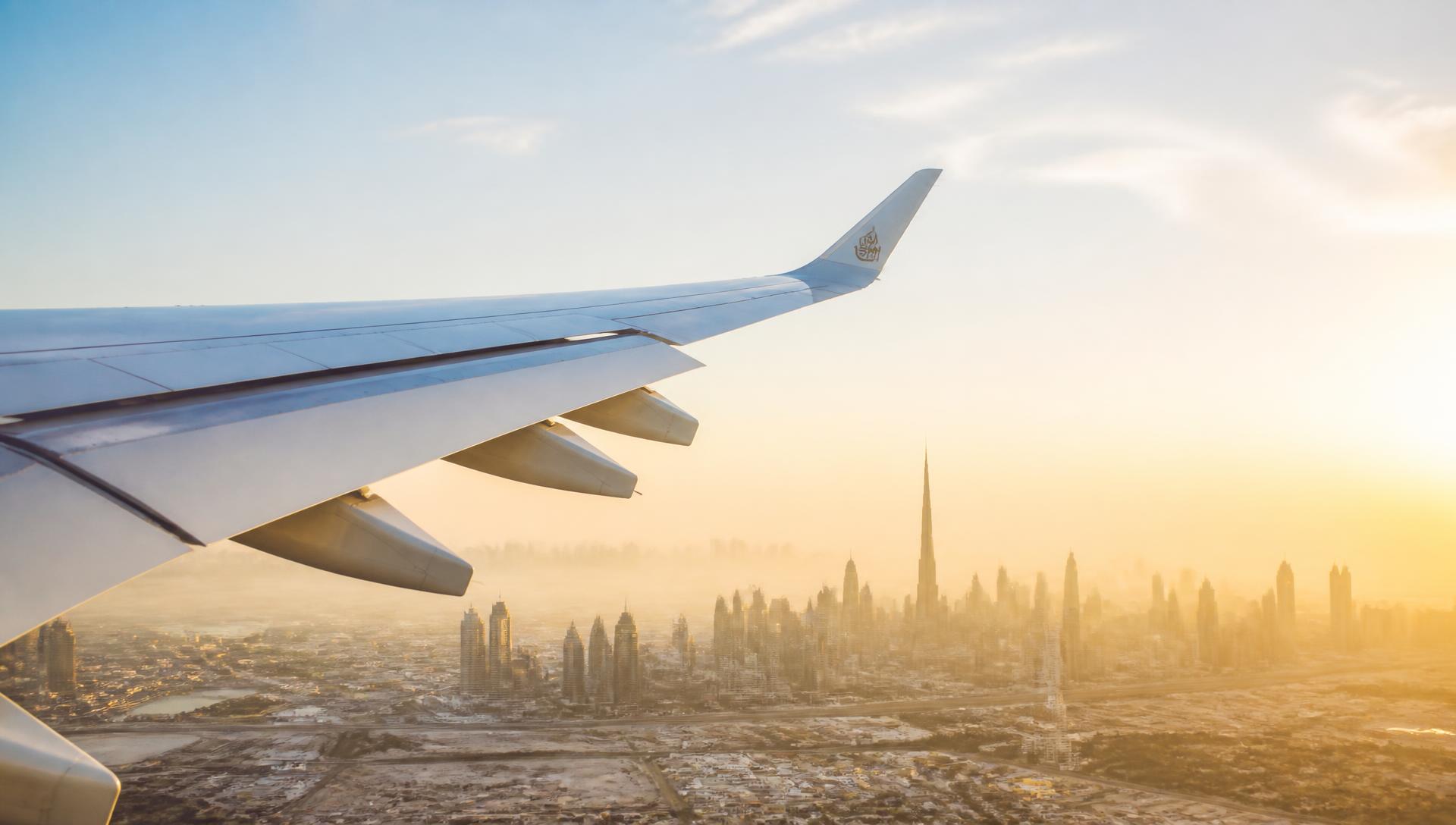Airplane wing above the Dubai skyline at sunrise